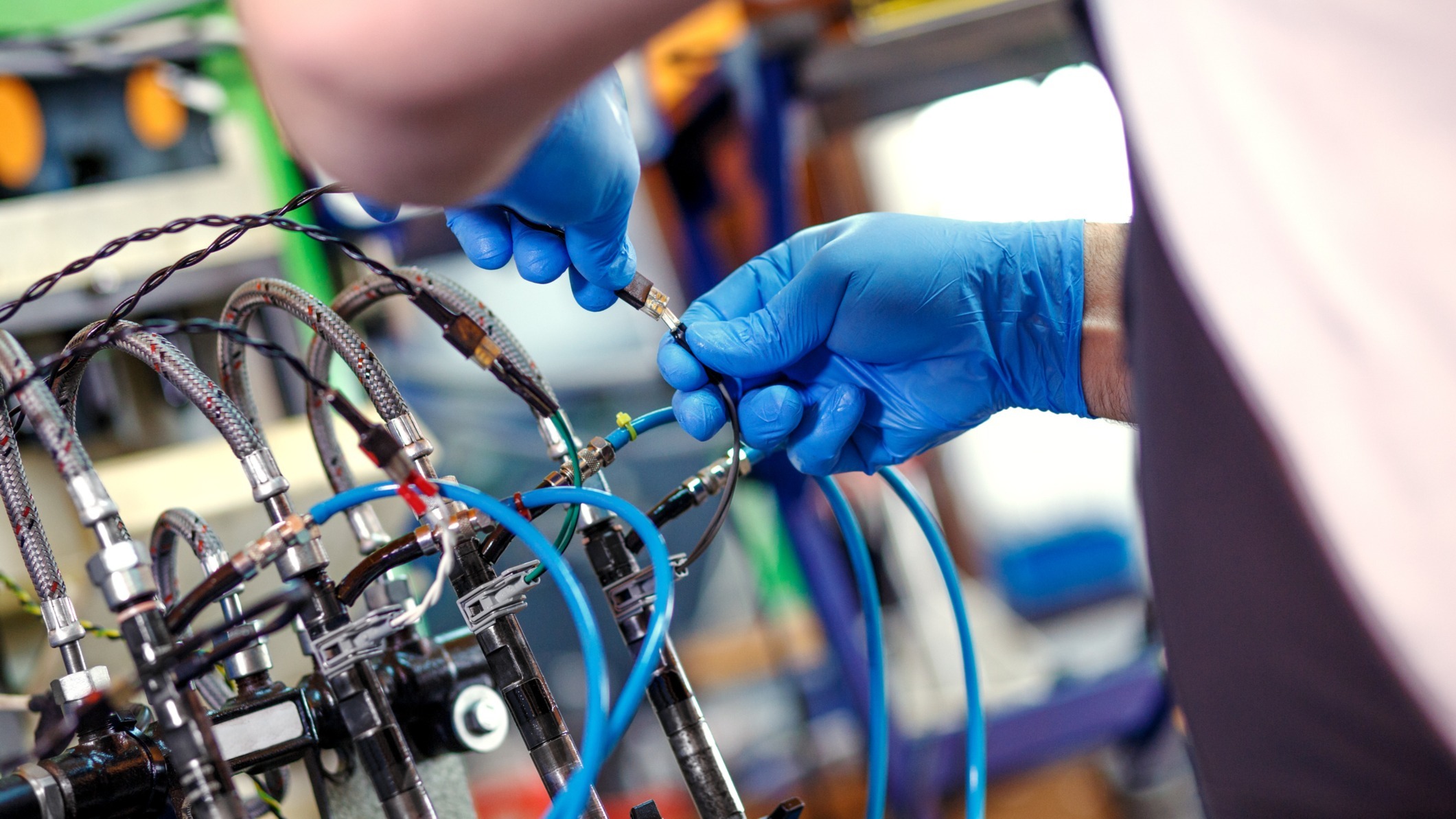 Serwisant w rękawicach podłącza przewody do testera